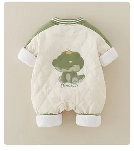 Close-up of quilted baby romper featuring cartoon dinosaur embroidery and green piping