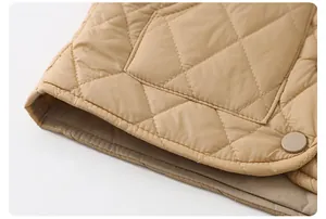 Dettaglio del gilet trapuntato kaki con cuciture a rombi e bottone a pressione in metallo