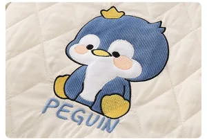 Detail of quilted baby romper fabric with cute penguin embroidery and crown design