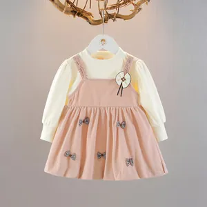 Dettaglio dell'abito da festa per bambina con gonna rosa a pieghe e piccoli fiocchi a pois