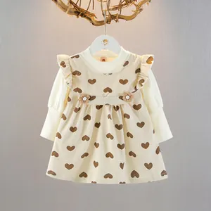 Dettaglio del vestito beige da bambina con stampa a cuori, volant e fiori decorativi in 3D