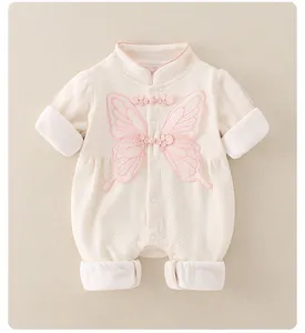 Détail d'un barboteuse bébé avec broderie papillon rose et boutons à nœuds