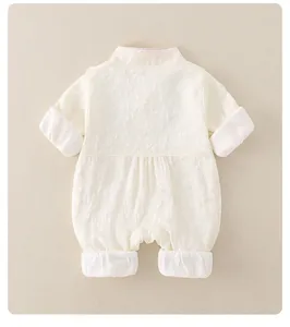 Detail of baby romper featuring delicate floral embossed texture and soft white cuffs