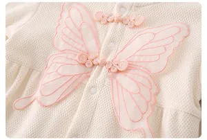 Détail d'un body en coton pour bébé avec tissu gaufré et broderie papillon rose