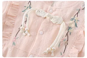 Detail of baby girl floral embroidery on pink jacquard fabric with pearl bow knot