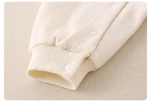 Détail d'un barboteuse pour bébé en maille gaufrée avec poignets côtelés et boutons pressions