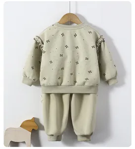 Back view of toddlers green sweatshirt set with black bow prints and ruffle shoulders