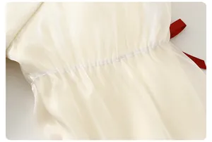 Dettaglio di tessuto in organza crema a pieghe ed elegante fiocco in nastro di raso rosso