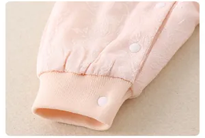 Detail of pink floral jacquard baby romper showing ribbed cuffs and white snap buttons
