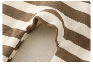 Dettaglio ravvicinato della tutina per neonati a righe marroni e beige in maglia morbida