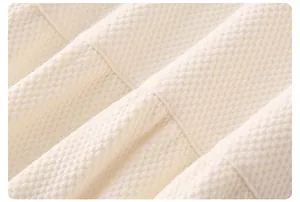 Détail macro de la texture gaufrée en coton crème et coutures fines du pyjama bébé