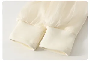 Dettaglio delle maniche a lanterna avorio con eleganti polsini in maglia a coste per bambina