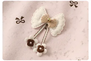 Close-up of quilted beige bow with embroidered flowers on pink floral kid hoodie
