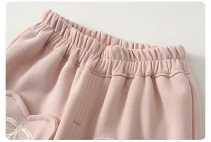 Detail of pink knitted joggers featuring an elastic waistband and heart embroidery patch