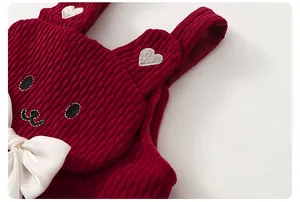 Dettaglio gilet di velluto a coste rosso con orecchie di coniglio e ricamo a cuore