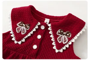Detail eines roten Cordkleids für Mädchen mit Spitzenkragen und Schleifenverzierung