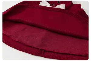 Dettaglio vestito in velluto rosso con fiocco di seta bianco e ricamo orsetto bimba