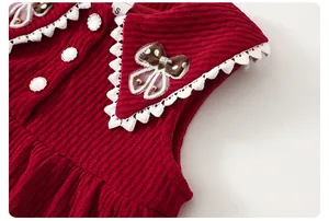 Detail eines roten Cordkleids mit Spitzenkragen, brauner Schleife und Perlenknöpfen