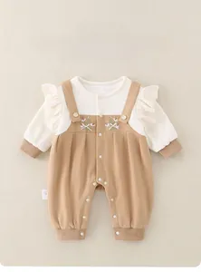 Close-up of cotton baby girl bodysuit with floral embroidery and lace ruffles