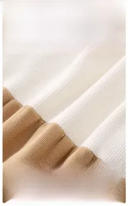 Close-up of soft ribbed cotton fabric in white and light brown for infant bodysuits