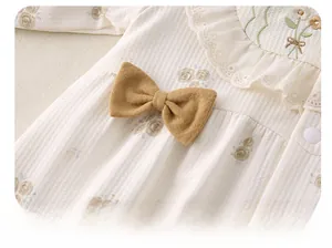 Detailansicht von Baby-Strampler mit Blumenmuster, gelber Schleife und Stickerei