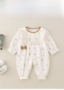 Detail eines Baby-Stramplers mit Blumenstickerei, Schleife und Druckknopfverschluss