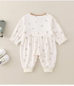 Detailaufnahme des beigen Baby-Einteilers mit Blumenmuster und weißen Rippbündchen