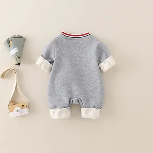 Gray baby romper with striped neck and white cuffs on a cozy beige background