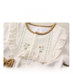 Detail eines Baby-Stramplers mit Blumenstickerei, Waffelstrick und Rüschenkragen