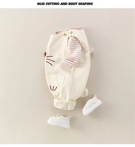 Detail of baby cotton overalls with cat embroidery and pink striped long sleeve shirt