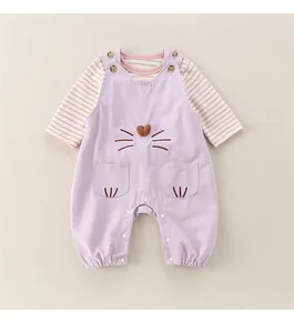 Detail of baby overall set showing cat embroidery and soft cotton texture on purple fabric