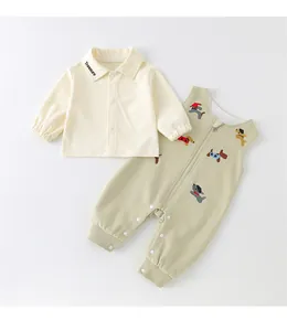 Detailed view of baby shirt with Treasure embroidery and green puppy overalls