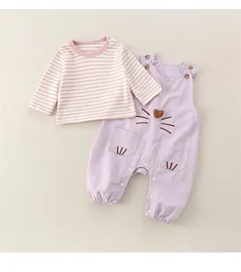 Detail of baby striped shirt and purple overalls with cute cat embroidery and soft fabric