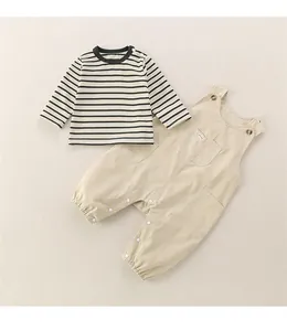 Détail de l'ensemble bébé 2 pièces avec t-shirt rayé et salopette kaki en coton