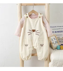 Close-up of baby beige overall and striped shirt with heart embroidery and wood buttons