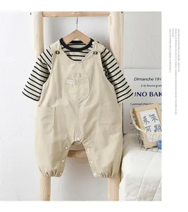 Détail d'un ensemble bébé avec chemise rayée et salopette beige sur échelle en bois