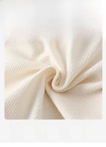 Close-up of soft cream knitted baby bodysuit fabric with breathable waffle texture