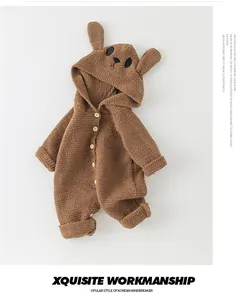 Close-up of brown plush baby romper with cute rabbit ears hood and wooden buttons