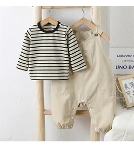 Détail d'un ensemble bébé avec t-shirt rayé et salopette kaki sur échelle