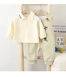 Detail of baby cotton set with cream jacket and green overalls featuring puppy patches