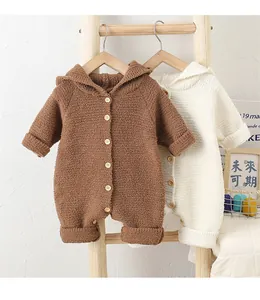 Detail of soft fleece hooded baby rompers with wooden buttons in earth tones