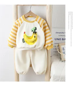 Detail of baby cotton tracksuit featuring banana embroidery and yellow striped raglan sleeves