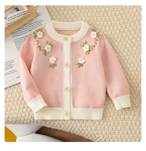 Gros plan sur un cardigan en tricot rose pour bébé avec broderie florale 3D