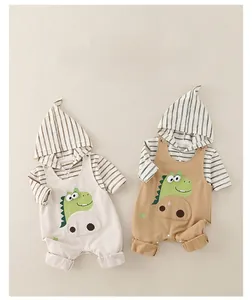 Dettaglio flat lay di body a righe con cappuccio e tute a forma di dinosauro beige e marroni