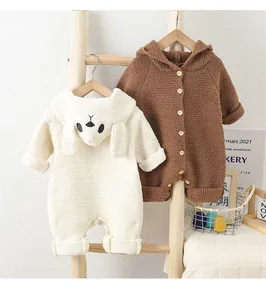 Detail of warm baby rompers in cream and brown with cute rabbit ears on a wooden ladder