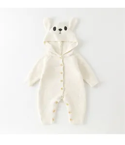 Detail of white infant romper with bunny ear hood and natural wooden buttons texture