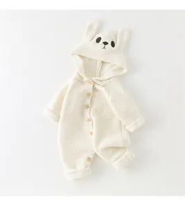 Detailed close-up of cream white knitted baby romper with cute bunny ear hood and wood buttons