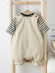 Ensemble bébé t-shirt rayé et salopette beige suspendu à une échelle en bois