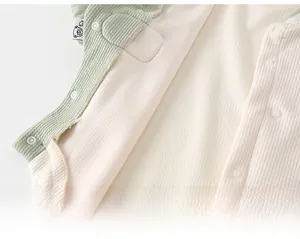 Detail of baby quilted vest with snap buttons and cute bear logo tag on soft fabric