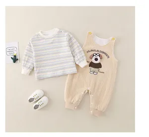 Detail of baby striped shirt and corduroy overalls with cartoon puppy graphic and soft shoes